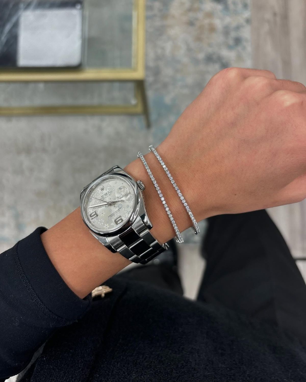 Person wearing a silver watch and bracelet on a blurred background