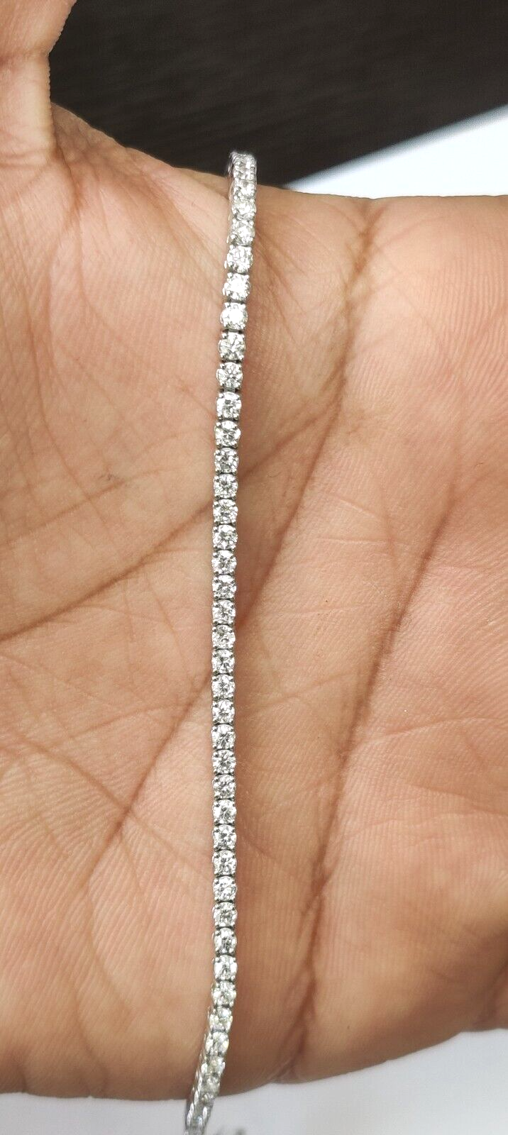 2mm white gold lab stone tennis bracelet on woman's hand against neutral home background